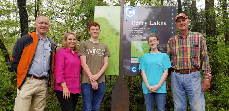 Group of people standing next to upright sign Cahaba Blueway Perry Lakes